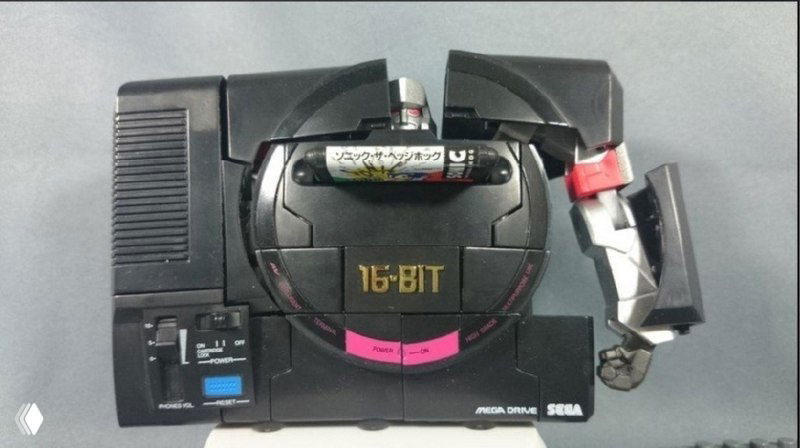 Вид сверху игрушки SEGA Mega Drive с открытым отсеком для батареек и частично повернутыми элементами механизма трансформации.
