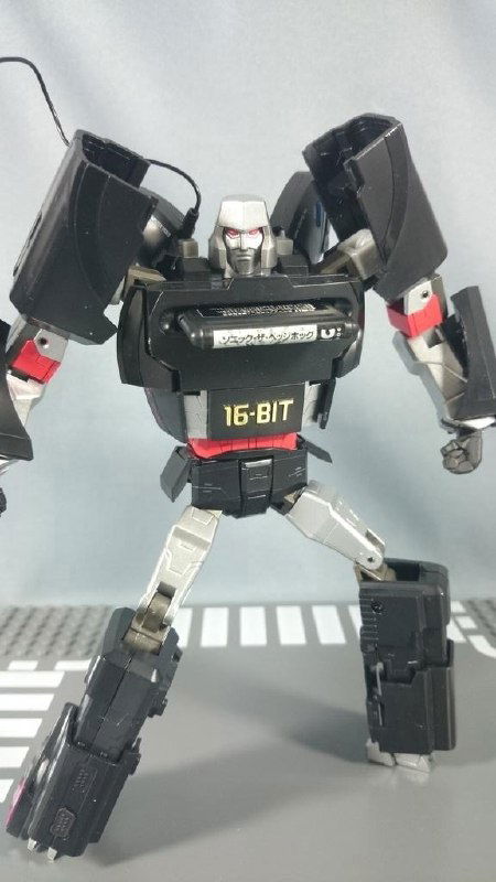 Готовая фигурка-робот в образе SEGA Mega Drive от Takara Tomy; полностью развернутая поза, видны ноги и руки трансформера.