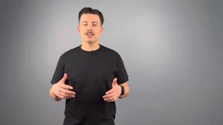 Мужчина в тёмной футболке на сером фоне, ведёт речь в камеру жестами — иллюстрация устной консультации по банкротству и объяснения этапов.