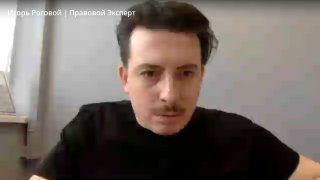 Игорь Роговой во время эфира: портрет ведущего в тёмной одежде у окна, говорящий о трендах банкротства физических лиц и ответах на вопросы аудитории.