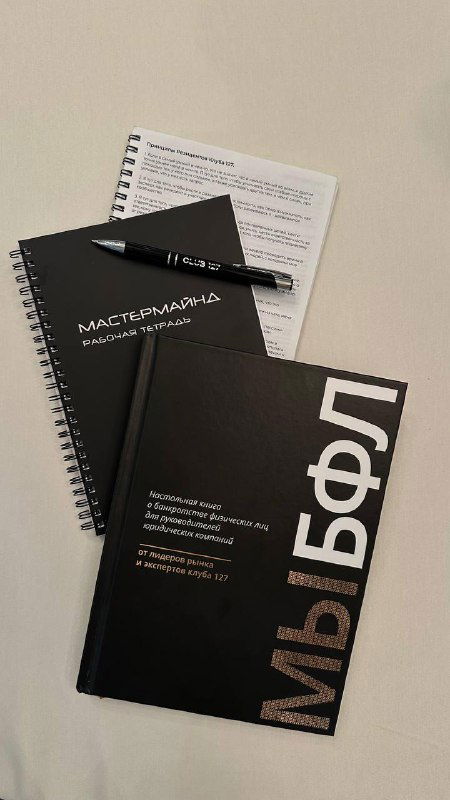 Крупный план книги и блокнотов на столе: обложка книги с кириллическим названием и фирменные блокноты для участников сообщества.