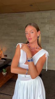 Модель в белом платье демонстрирует разноцветные украшения Coeur de Lion — колье, браслеты и серьги; интерьер магазина виден на заднем плане, рекламный контекст.