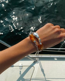 Браслет Ciclon LIQUID на фоне морской воды: прозрачные и янтарные муранские элементы отражают солнечный блик и подчёркивают летнюю концепцию коллекции.