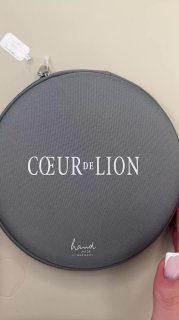 Круглая серая коробка Coeur de Lion с белым логотипом — стильная упаковка для украшений, вид сверху на изделие и брендинг.