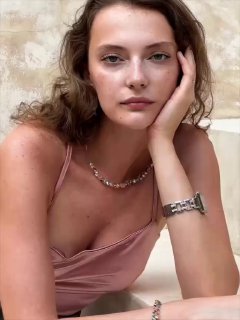 Модель в розовом топе демонстрирует колье Coeur de Lion с мелкими сверкающими кристаллами Swarovski на светлом нейтральном фоне