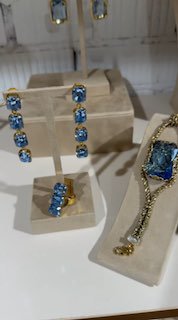 Серьги и кольцо с крупными синими камнями на белых подставках, демонстрация коллекции ярких украшений авторской бижутерии Rosone в магазине.
