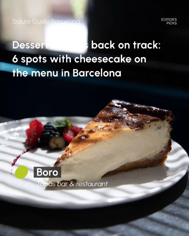 Classic cheesecake slice on a white plate with berry garnish, served at a cozy bar and restaurant table in Barcelona.
