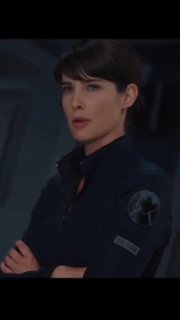 Женщина в тёмной форме с собранными волосами, задумчиво смотрит в сторону; портрет в кинематографичном освещении, символ лидерства и профессионального роста.