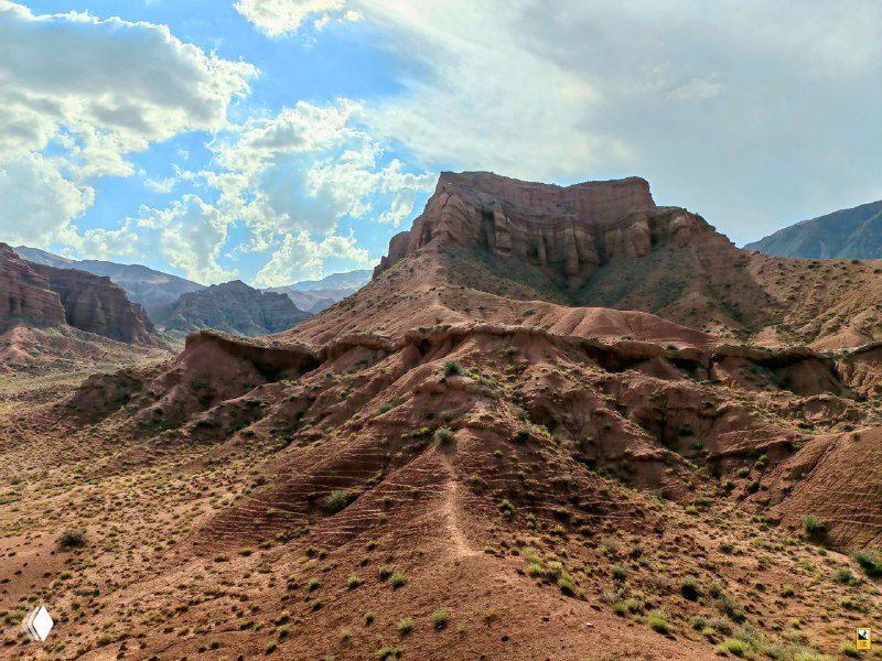 Обширные овраги и обломанные скальные образования каньона; драматичное небо создаёт «дикозападную» атмосферу в кадре.