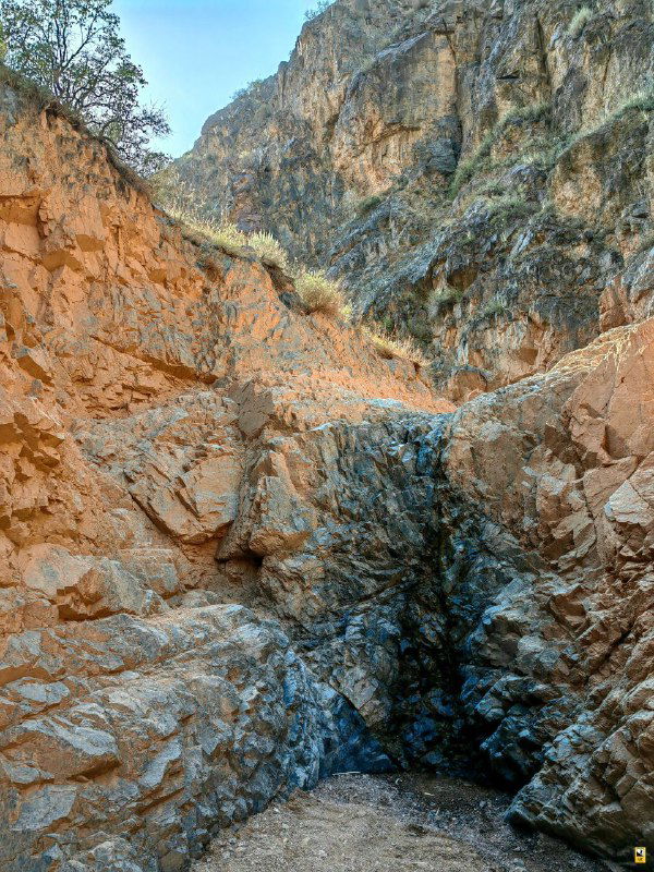 Узкий участок каньона с высокими каменными стенами и небольшим водопадом/стоком в сухом русле — сложный участок тропы.
