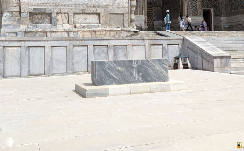 Мраморная плита на главной площади Регистан: видимая могила на переднем плане, ступени и фасад медресе на заднем фоне, людской масштаб.
