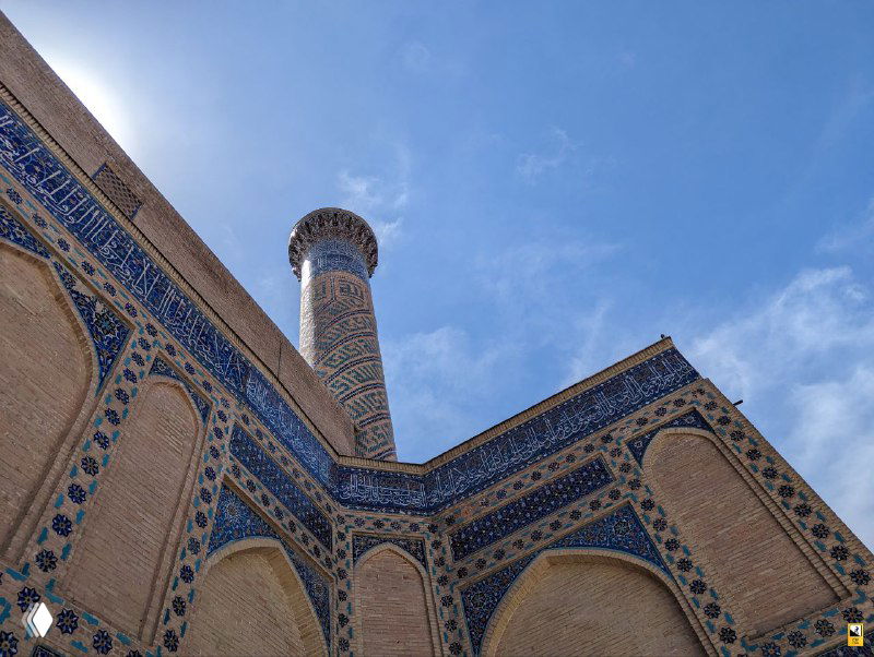 Крупный план угла архитектуры с мозаикой и минаретом: глазурованные плитки, геометрические узоры и переходы между кирпичом и декором.