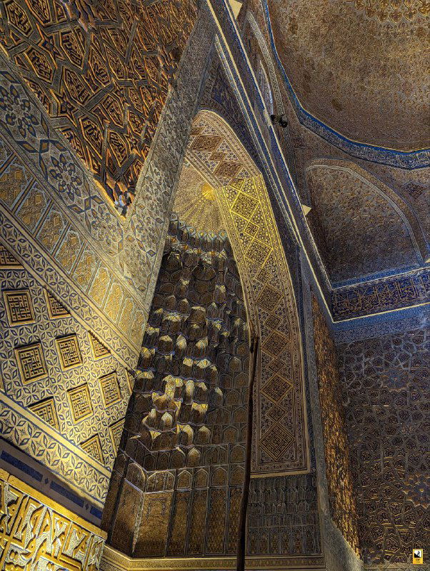 Фрагмент интерьера с декоративными нишами и декоративными сводами: игра света и тени на элементной резьбе и мозаике в помещении мавзолея.