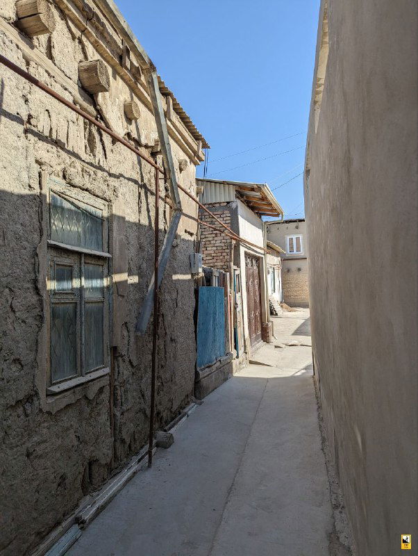 Узкая песчано-одноэтажная улочка Бухары с домами в традиционном стиле; тихий переулок для пряток от солнца и прогулок.