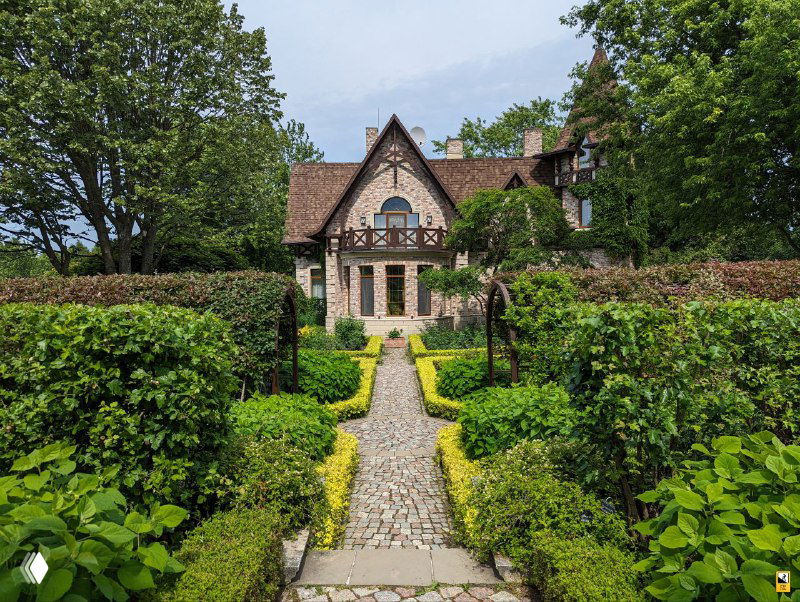 Дорога и симметричная аллея ведут к другому фасаду усадебного дома, возле которой размещены аккуратные бордюры и живые изгороди.