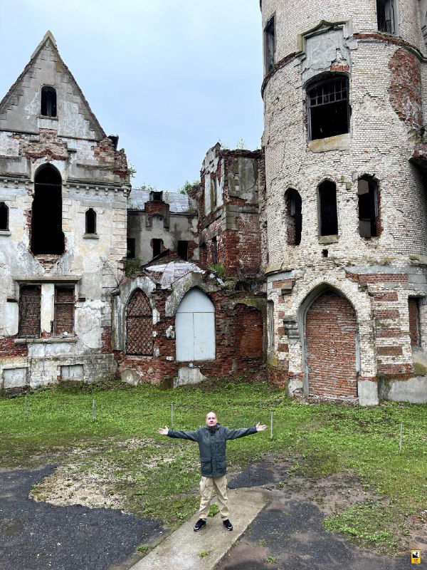 Автор заметки на фоне полуразрушенных стен усадебного дома «Замок мира», руки в стороны и масштаб усадьбы виден в окружении развалин.
