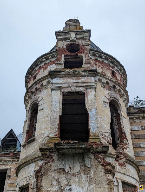 Разрушенная круглая башня с пустыми арками и облупившейся штукатуркой — отчетливые следы времени и утраты исторической отделки фасада.