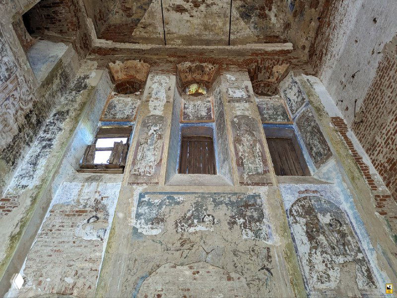 Интерьерная часть с фрагментами фресок и архитектурными следами часовни внутри церкви: потёртые изображения, ниши и полосы штукатурки.