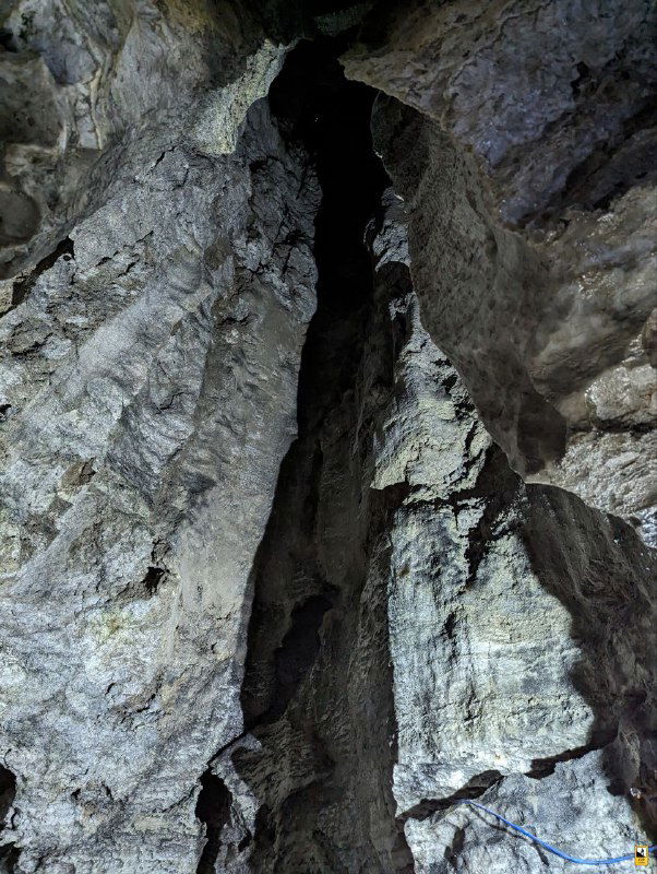 Узкий вертикальный разлом и высокий карстовый «колодец» внутри пещеры, вид снизу вверх; впечатляет масштаб и глубина системы ходов Кунгурской ледяной пещеры, фото экскурсии.