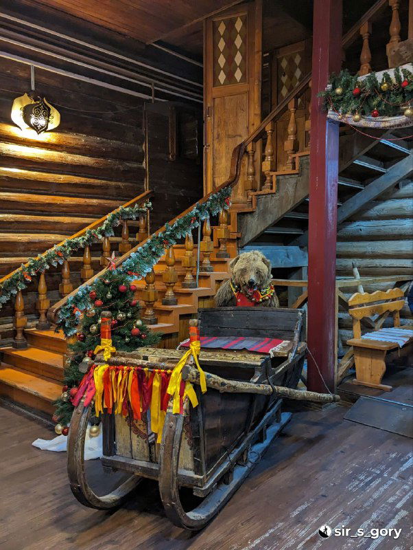Деревянная лестница и санки в тереме: украшенные лентами предметы, тёплый свет и деревянная отделка для атмосферных фотосессий.