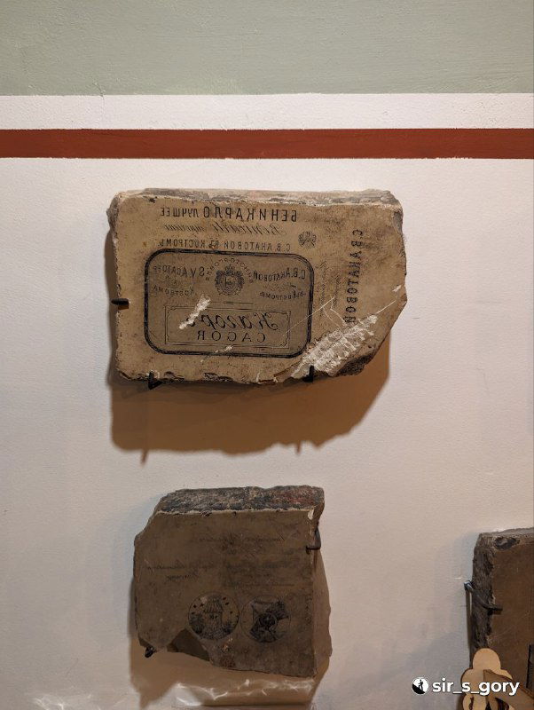 Фрагменты старых упаковок и маркировки на стенде в музее‑магазине, демонстрация истории упаковки и товарного наследия региона.