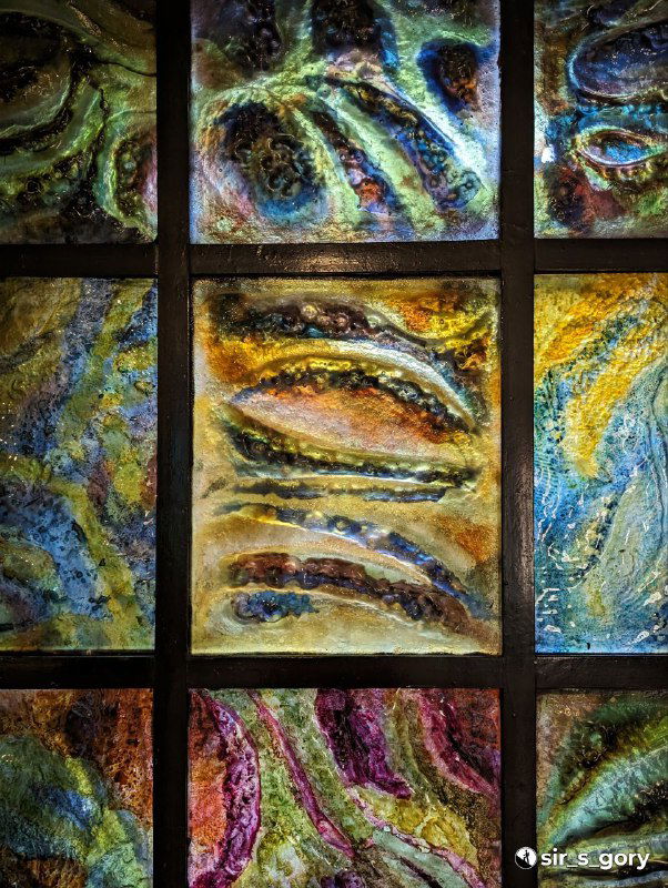 Радужные витражи или декоративные панели с янтарными мотивами и мозаичным рисунком в экспозиции музея.