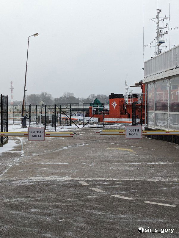 Портовая зона Балтийской косы зимой: пустая набережная, заграждения и небольшие постройки, облепленные мокрым снегом и холодным ветром