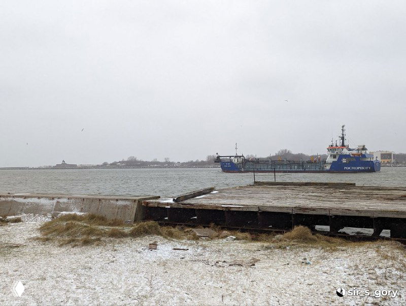 Зимний берег Балтийской косы: низкий пляж, штормовые волны, частично покрытые снегом деревянные настилы и покинутая набережная