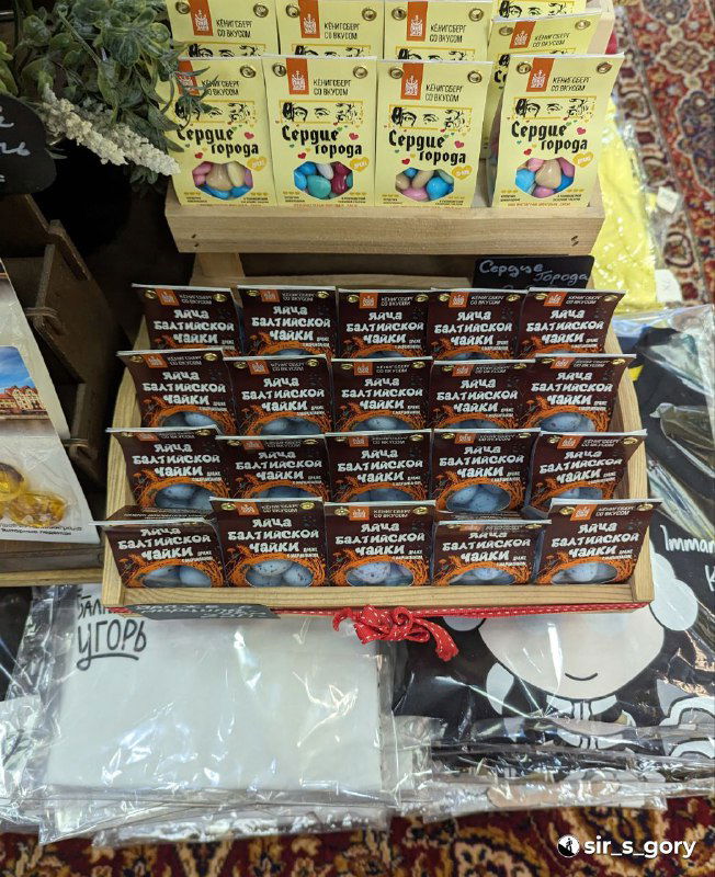 Стойка с коробками марципановых сладостей и сувениров: многообразие вкусовых вариантов и яркие этикетки в магазине.