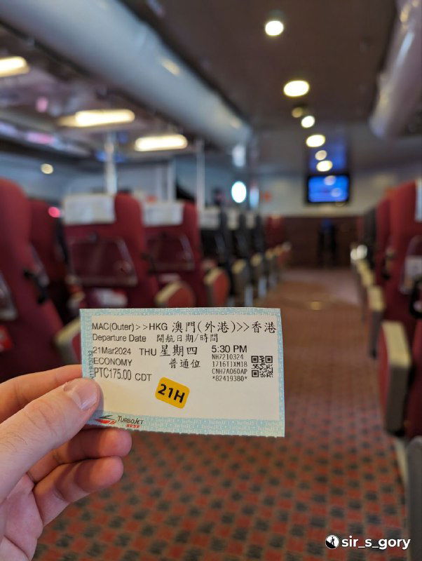 Крупный план билета на паром в руке пассажира: внутри салона видны ряды кресел, информационное табло и мягкая внутренняя обстановка.