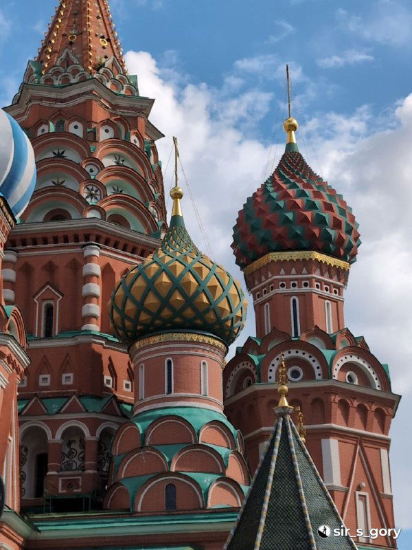 Крупный план двух луковичных куполов собора: геометрический орнамент, контраст зелёно‑жёлтых и красных оттенков на фоне неба.