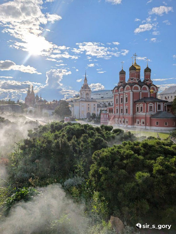 Панорамный вид на Покровский собор и зелёные насаждения парка Зарядье: утренний пар, архитектура и голубое небо с облаками
