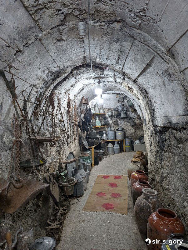 Внутренний коридор бывшего бункера, превращённого в музей, со сводчатым потолком и выставленными керамическими предметами и старинными вещами.