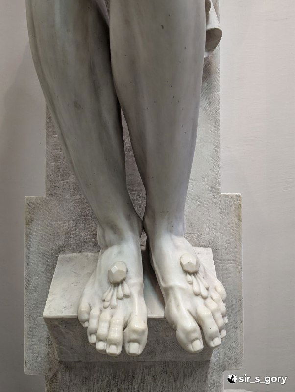 Крупный план мраморных стоп и ног распятого, детальная проработка и следы крепления на постаменте в экспозиции краеведческого музея.
