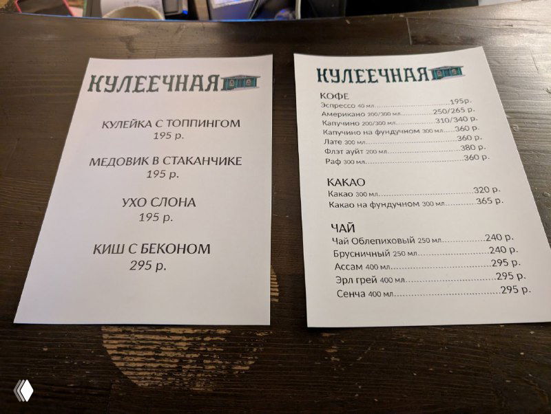 Меню кафе, распечатанные листы с перечислением блюд и цен, снимок сделан на столе внутри небольшого заведения в Плёсе.