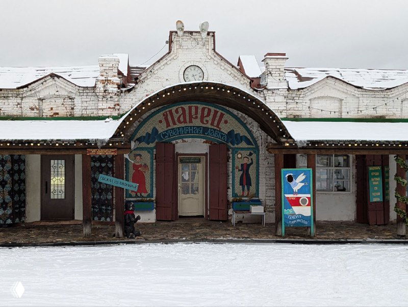 Фасад старого здания в Плёсе зимой: заснеженная крыша, вывески и пустая улица, общая панорама центральной части города в несезон.