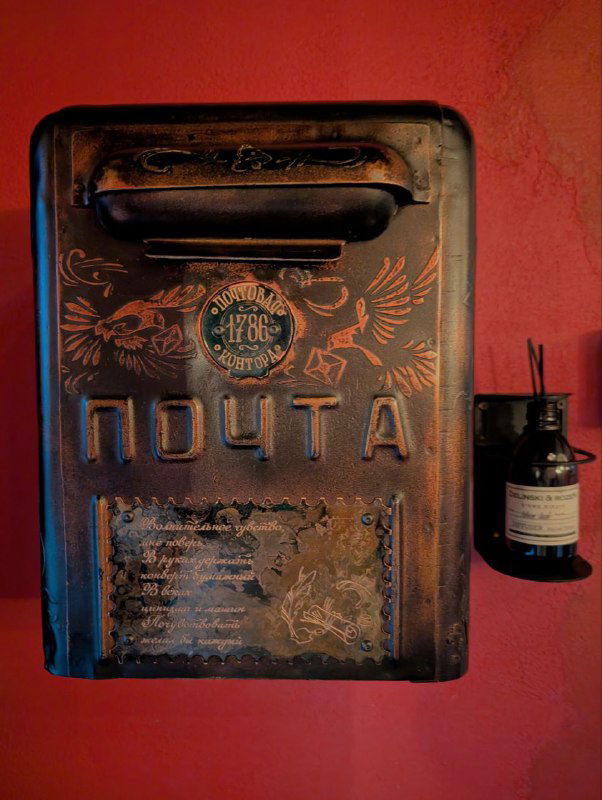 Старинный декоративный почтовый ящик с надписью «ПОЧТА» внутри интерьера ресторана — элемент атмосферы и отсылка к истории здания.