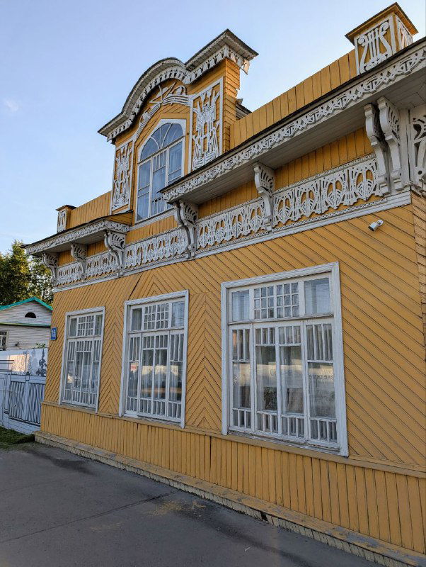 Деревянный особняк в Вологде с характерным декором в виде ажурной резьбы и декоративным фронтоном над высоким окном на втором этаже