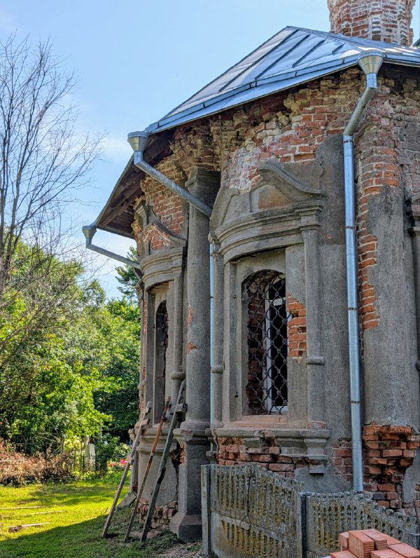 Угловой фрагмент приархитектурного строения с кронштейнами и подпорками, видны восстановительные работы у маленьких окон и цоколя.