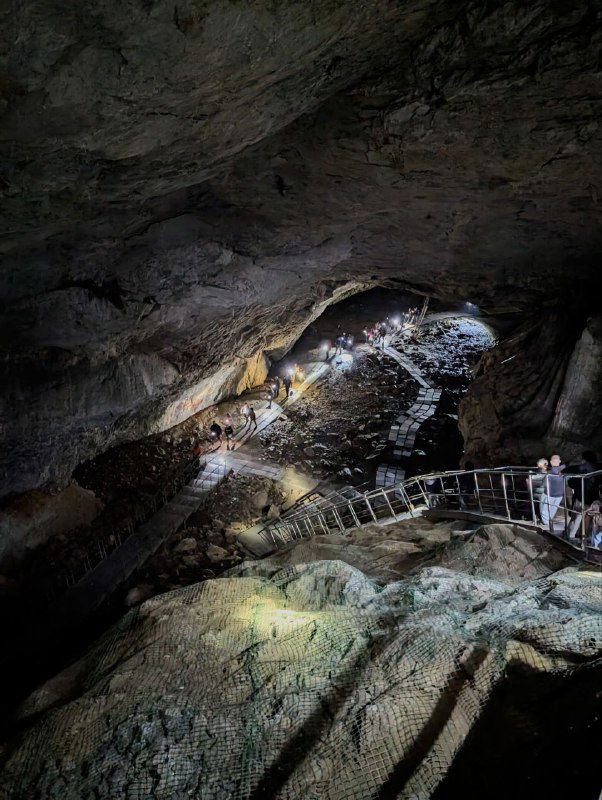 Внутренний вид экскурсионного маршрута Шульган‑Таш: мостики и ограждения в большом зале пещеры, посетители на тропе и масштаб карстовой камеры.