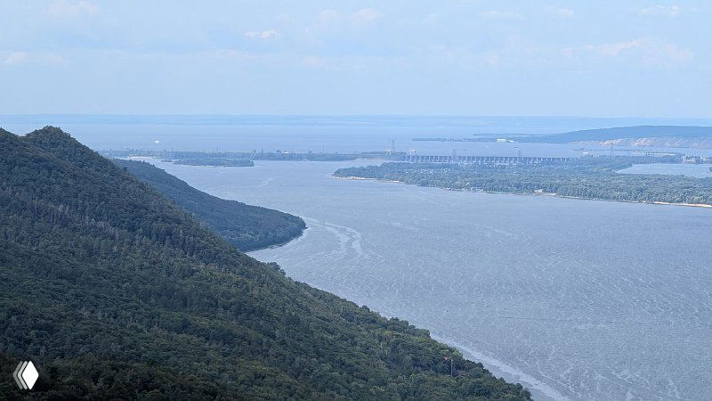 Широкий изгиб реки Волга между лесистыми хребтами, вода и далекий берег на горизонте — вид с гребня в заповедной зоне Самарской луки.