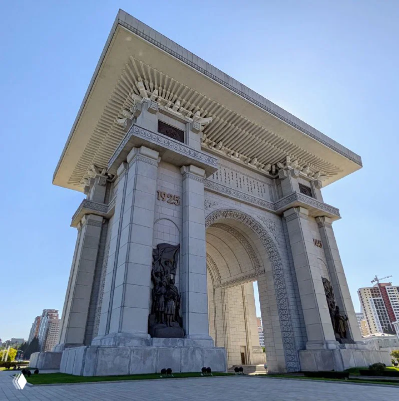 Крупный план боковой части Триумфальной арки: массивные колонны, орнамент и монументальные скульптуры в нишах под крышей арки.