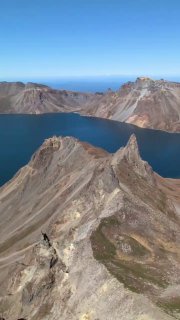 Панорамный вид на острую гряду внутри кратера и гладь озера Чон, с куполообразными склонами и бирюзовой водой.