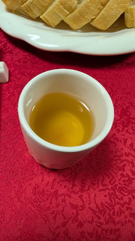 Чашка с тёмно-жёлтым картофельным чаем на столе рядом с хлебом и скатертью — необычный напиток из поездки автора.