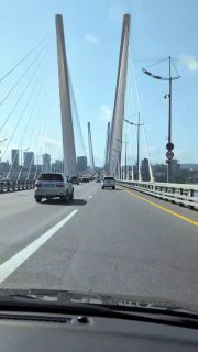 Вид с проезжей части на пилоны и тросы вантового моста: ракурс с дороги показывает конструктивные элементы и городской горизонт.