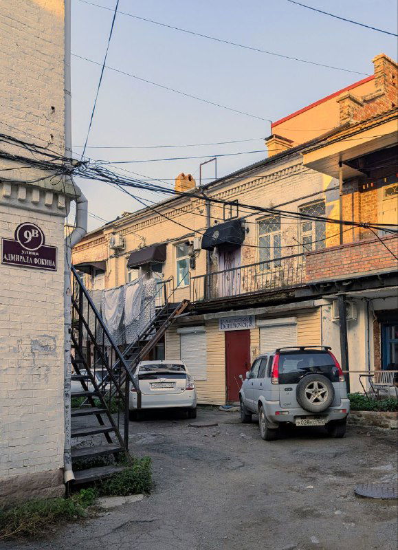 Узкий двор с металлической лестницей и переплетением проводов между домами — плотная застройка и характерные детали Миллионки.