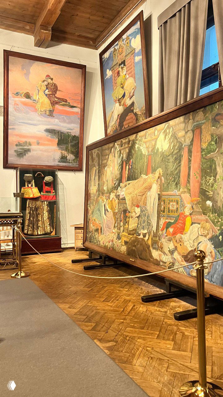 Зал музея с крупными полотнами Виктора Васнецова: картины в рамах, паркетный пол и музейная ограда на переднем плане.