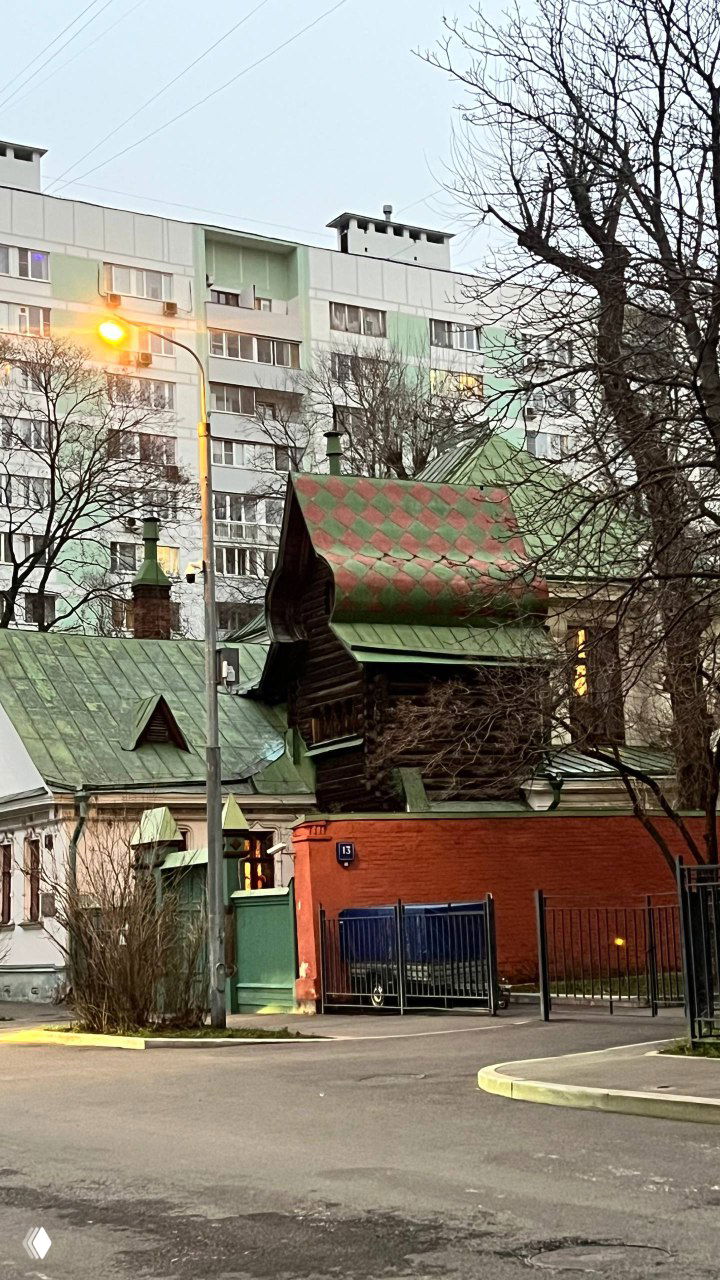 Вид снаружи: деревянный дом‑музей Васнецова с зелёной кровлей и декоративными элементами на фоне обычных многоэтажек.