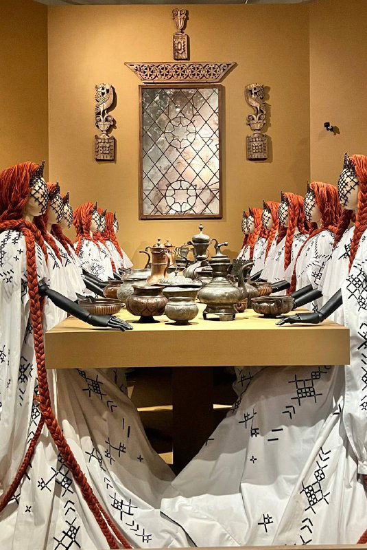 Манекен в длинном платье с вуалью и перьями — тёмная подсветка и текстурные слои подчёркивают драматическую подачу одежды.