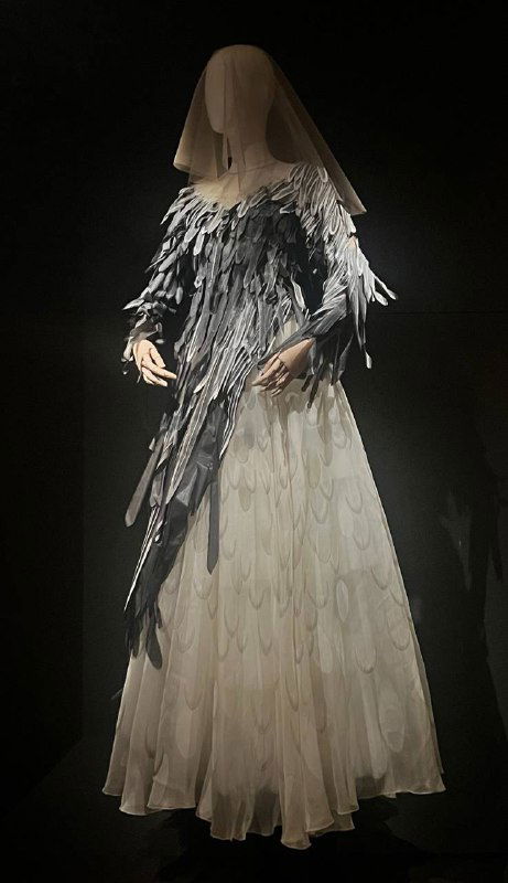 Группа манекенов в ярких театрализованных костюмах с объемными аппликациями и сложной конструкцией головных уборов на нейтральном фоне.